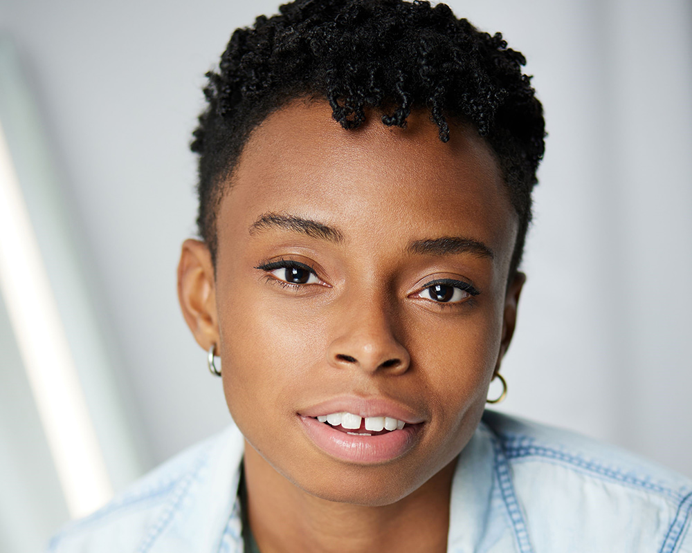 Portrait of a smiling student in a light blue shirt against a soft gray background